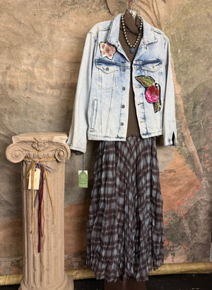 Flowy plaid midi skirt in blue-gray tones styled with patched denim jacket and pearl necklace on boutique display - 1
