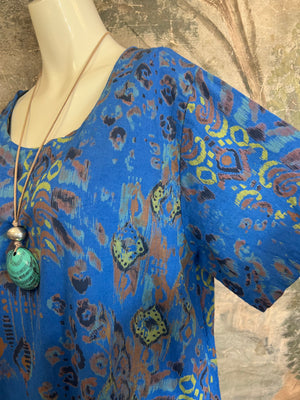 Blue ikat paint splotch print tunic dress with short sleeves, paired with black leggings and turquoise pendant necklace - 6