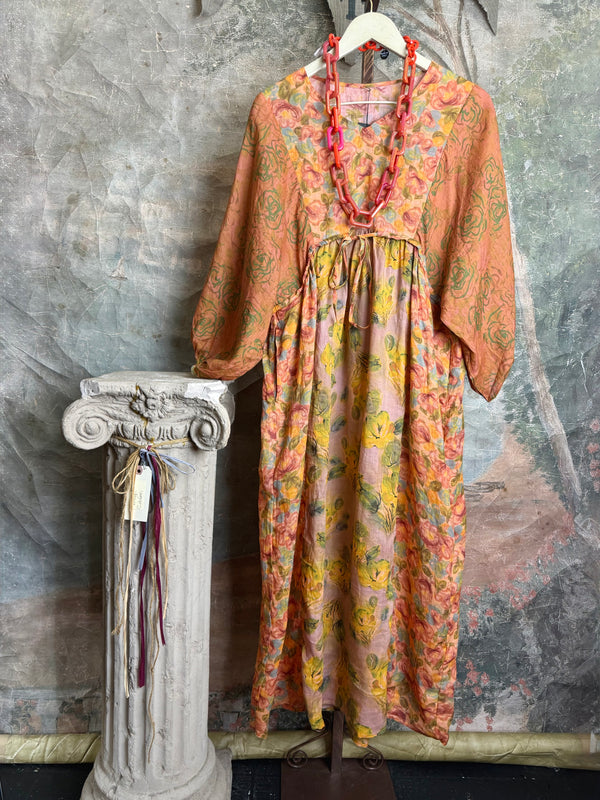 Woman wearing DYM90081 Bloomspell Maxi Dress in orange floral print with pink Converse sneakers in boutique setting - 3