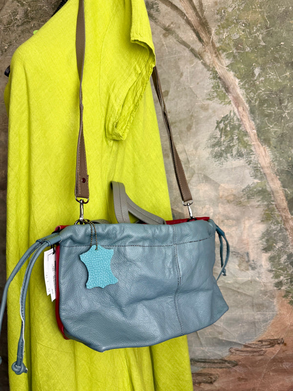 Alma shoulder bag in red pebbled leather with gray handles and teal accents on lime green dress mannequin - 6