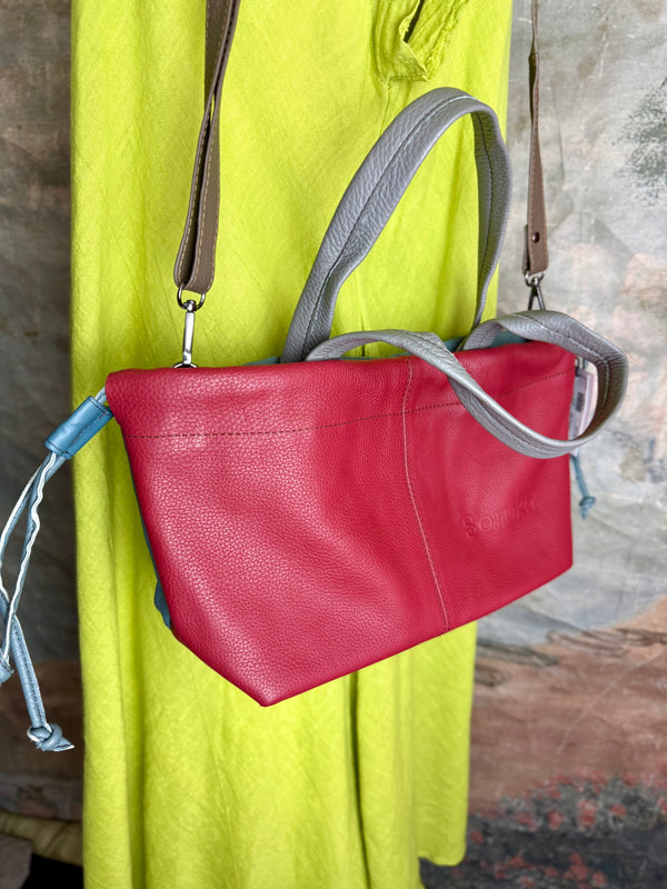Alma shoulder bag in red pebbled leather with gray handles and teal accents on lime green dress mannequin - 2