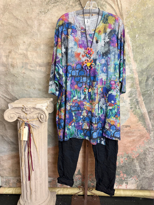 Oversized crew pullover in vibrant multicolor abstract print with flower necklace, paired with black pants on mannequin - 1