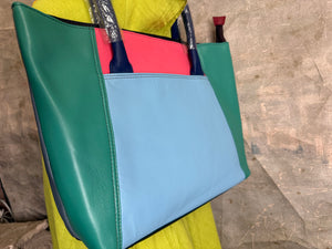 Colorblock leather tote bag in teal, light blue, and coral pink on mannequin with lime green dress, navy handles - 2