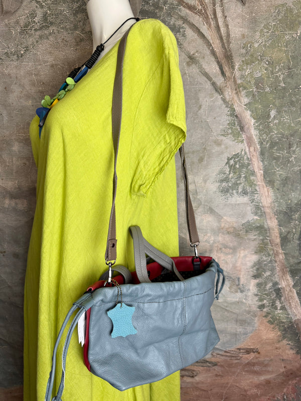 Alma shoulder bag in red pebbled leather with gray handles and teal accents on lime green dress mannequin - 7