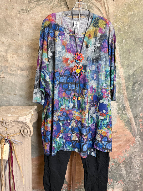 Oversized crew pullover in vibrant multicolor abstract print with flower necklace, paired with black pants on mannequin - 2