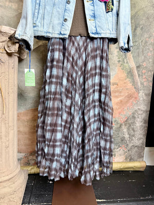 Flowy plaid midi skirt in blue-gray tones styled with patched denim jacket and pearl necklace on boutique display - 2