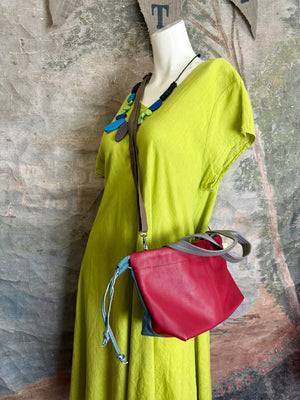 Alma shoulder bag in red pebbled leather with gray handles and teal accents on lime green dress mannequin - 1