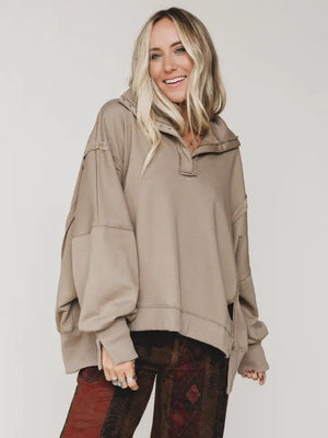 Woman wearing oversized taupe quarter-zip pullover sweatshirt with exposed seams and ribbed cuffs - 1