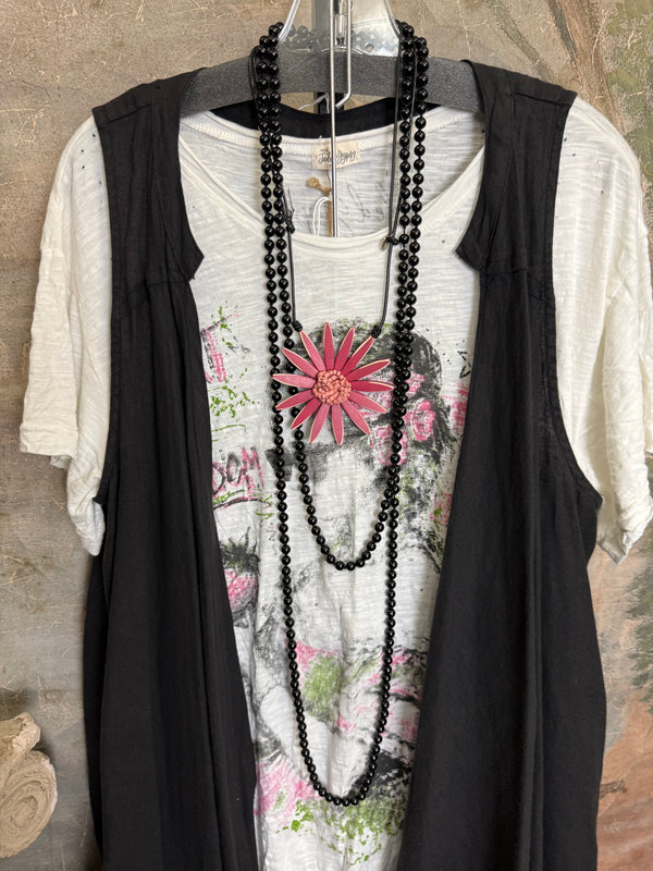 Long black sleeveless open front duster vest styled with graphic tee, gingham pants, and black beaded necklace on hanger - 4