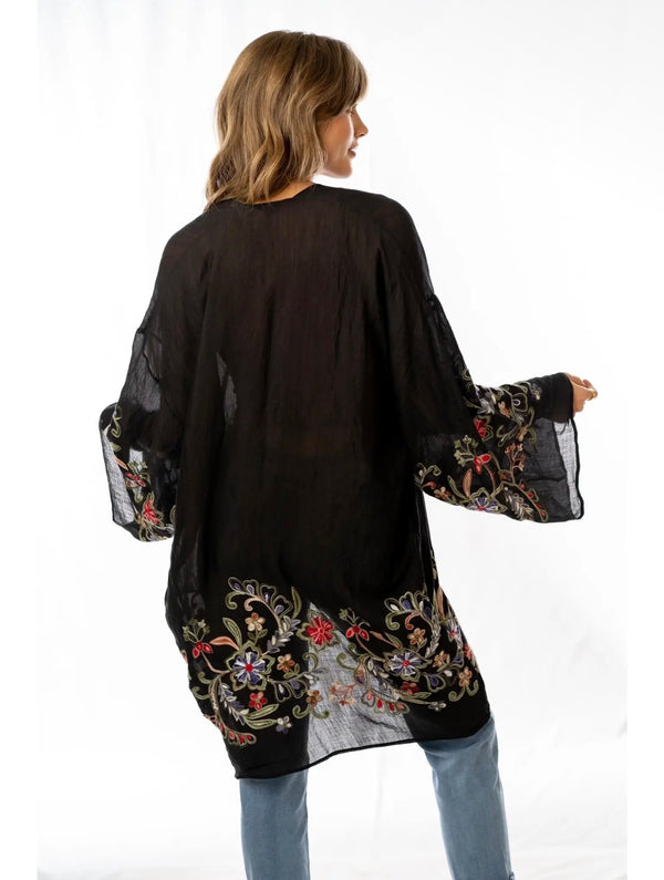 Woman wearing black floral embroidered kimono cardigan with wide sleeves over rust crop top and jeans - 4
