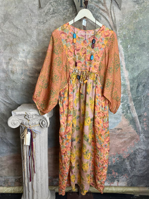Woman wearing DYM90081 Bloomspell Maxi Dress in orange floral print with pink Converse sneakers in boutique setting - 2