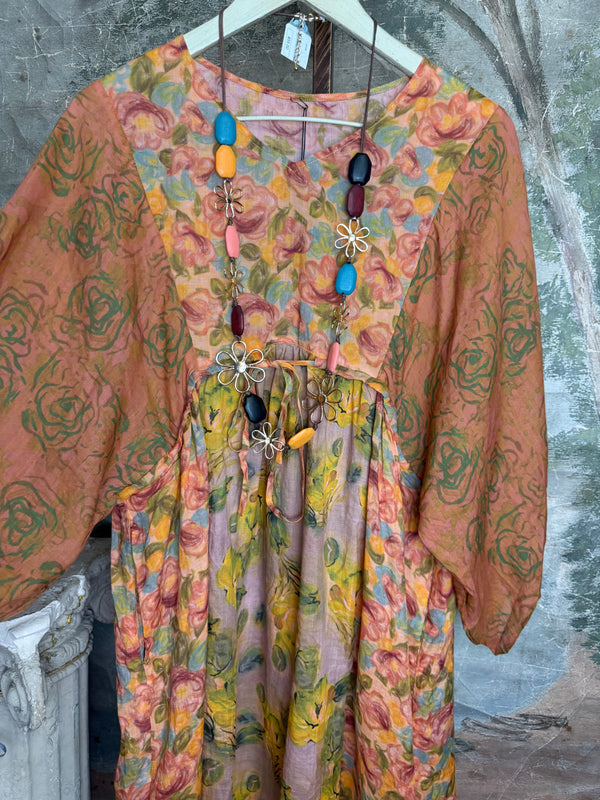 Woman wearing DYM90081 Bloomspell Maxi Dress in orange floral print with pink Converse sneakers in boutique setting - 5