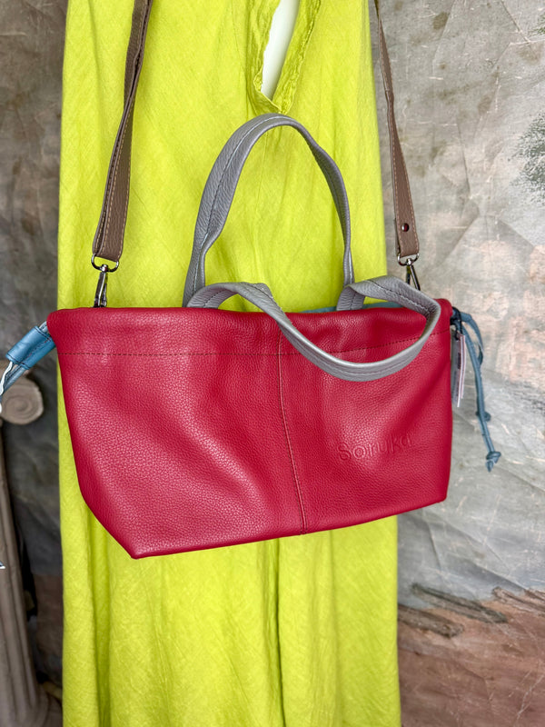 Alma shoulder bag in red pebbled leather with gray handles and teal accents on lime green dress mannequin - 4