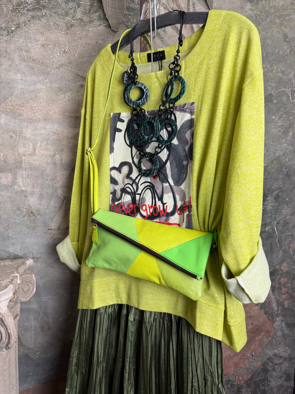 Lime green knit top with Never Grow Up graphic print, styled with green chain ring necklace and olive pleated skirt - 4
