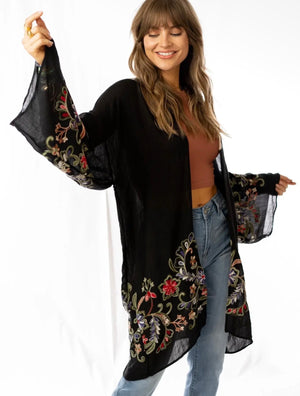 Woman wearing black floral embroidered kimono cardigan with wide sleeves over rust crop top and jeans - 1