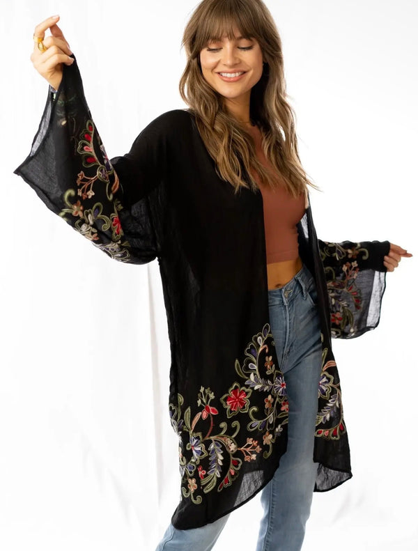 Woman wearing black floral embroidered kimono cardigan with wide sleeves over rust crop top and jeans - 1