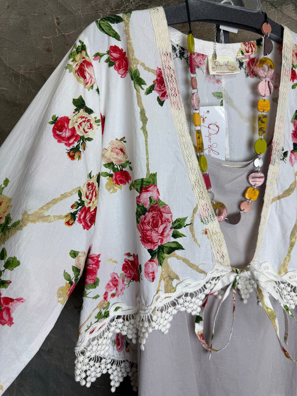 White floral kimono cardigan with pink roses and crochet lace trim displayed over gray tank top on hanger - 5