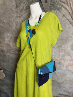 Mila color-block crossbody bag in teal, blue, and navy leather with turquoise strap, styled on mannequin with lime dress - 1