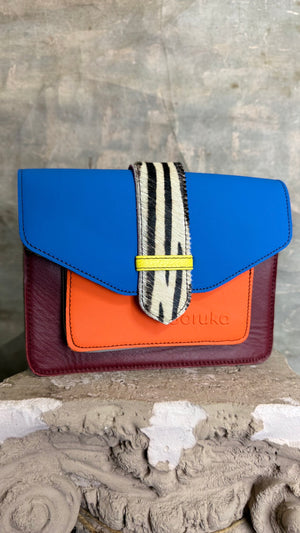 Goruka Grace Reversible Loop-B colorblock leather bag in blue, burgundy, orange with zebra print strap on stone column - 2