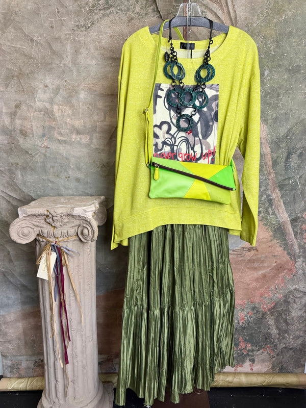 Lime green knit top with Never Grow Up graphic print, styled with green chain ring necklace and olive pleated skirt - 2