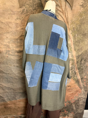 Olive green ribbed cotton cardigan with denim patchwork LOVE letters on back, displayed on mannequin - 7