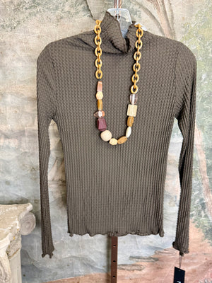 Olive green waffle knit turtleneck long sleeve fitted top displayed with chunky beaded statement necklace on hanger - 1