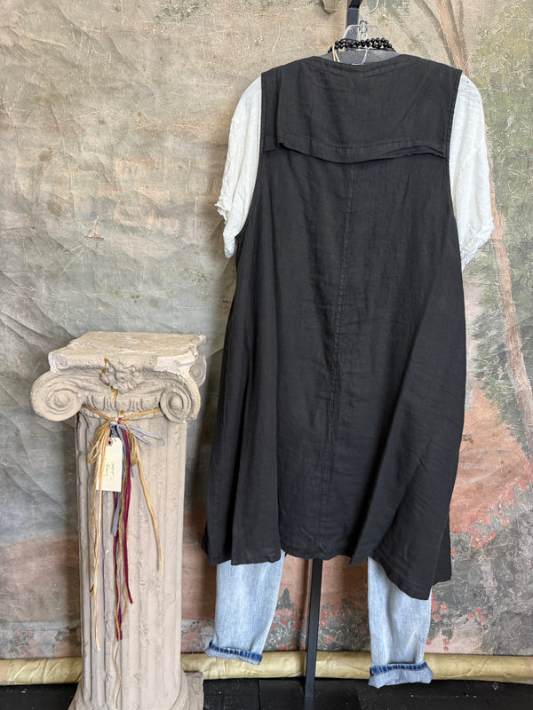 Long black sleeveless open front duster vest styled with graphic tee, gingham pants, and black beaded necklace on hanger - 7