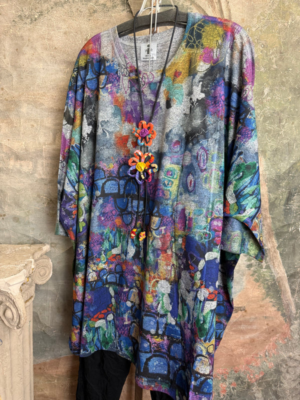 Oversized crew pullover in vibrant multicolor abstract print with flower necklace, paired with black pants on mannequin - 6