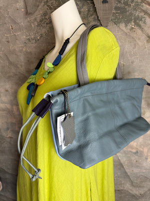 Gray leather shoulder bag with drawstring closure displayed on mannequin wearing lime green dress and colorful beaded ne - 2