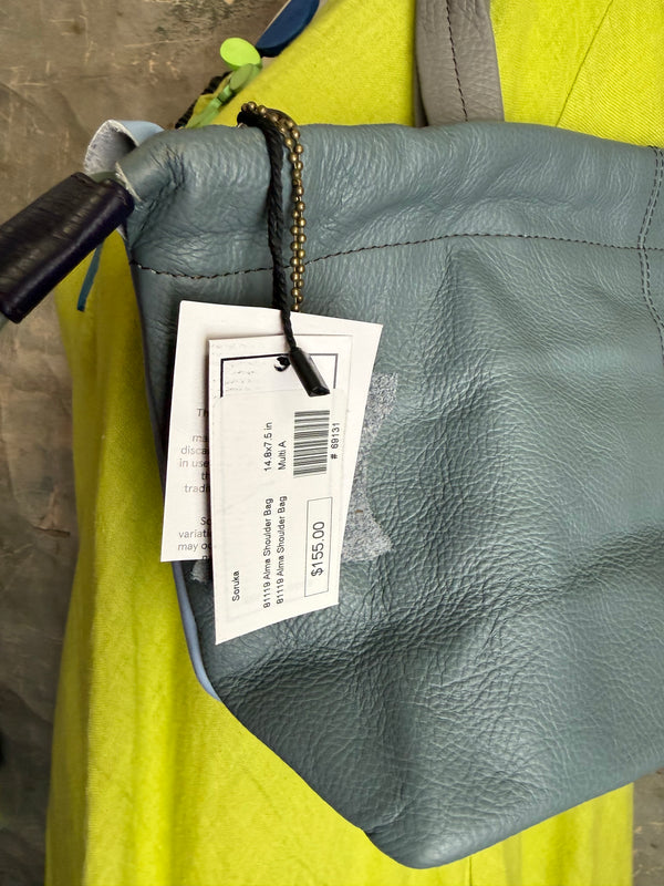 Gray leather shoulder bag with drawstring closure displayed on mannequin wearing lime green dress and colorful beaded ne - 4