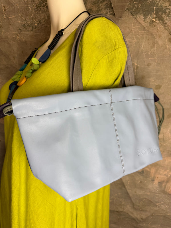 Gray leather shoulder bag with drawstring closure displayed on mannequin wearing lime green dress and colorful beaded ne - 7