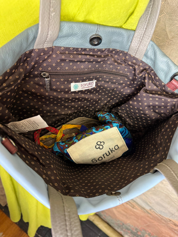 Gray leather shoulder bag with drawstring closure displayed on mannequin wearing lime green dress and colorful beaded ne - 10