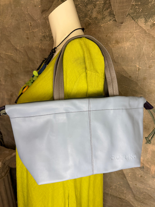 Gray leather shoulder bag with drawstring closure displayed on mannequin wearing lime green dress and colorful beaded ne - 15
