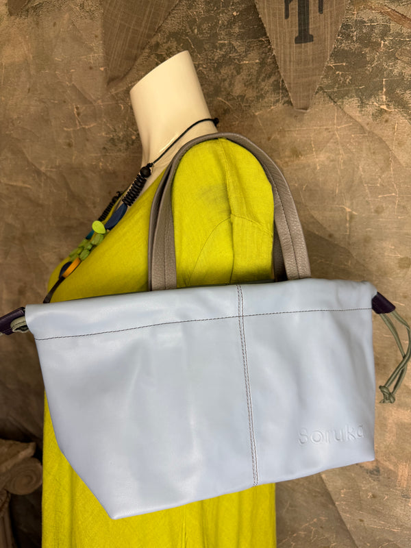 Gray leather shoulder bag with drawstring closure displayed on mannequin wearing lime green dress and colorful beaded ne - 16