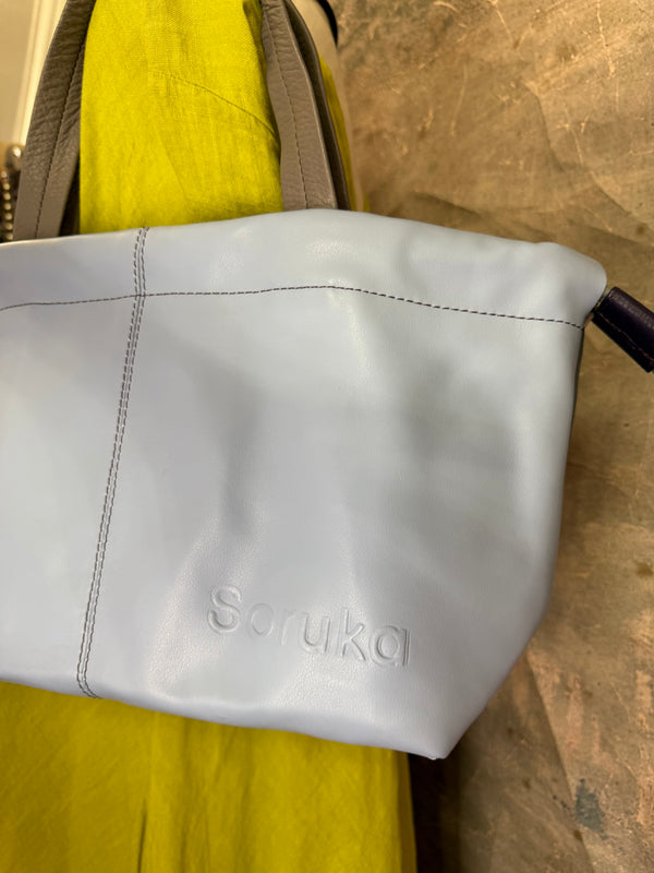 Gray leather shoulder bag with drawstring closure displayed on mannequin wearing lime green dress and colorful beaded ne - 17