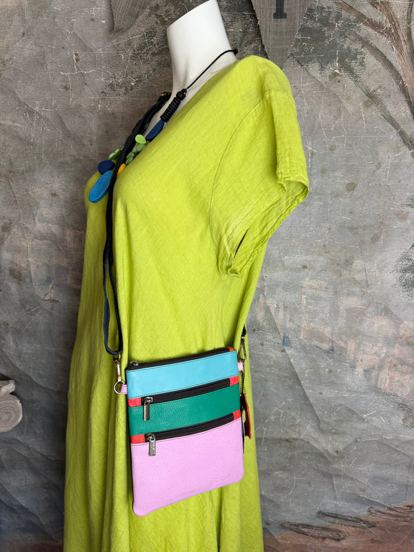 Colorblock crossbody bag in teal, green, and pink with zip pockets on lime green dress mannequin - 1