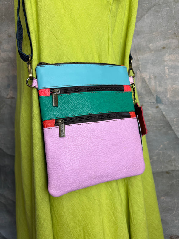 Colorblock crossbody bag in teal, green, and pink with zip pockets on lime green dress mannequin - 4