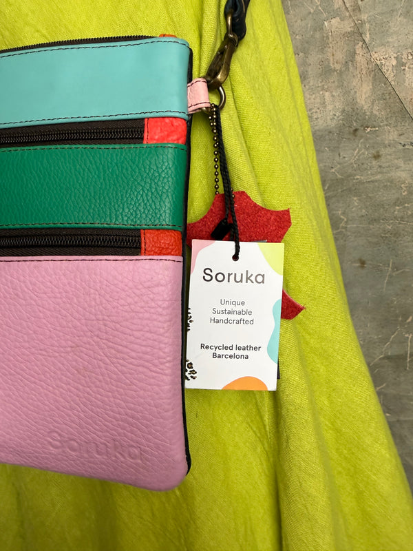Colorblock crossbody bag in teal, green, and pink with zip pockets on lime green dress mannequin - 11