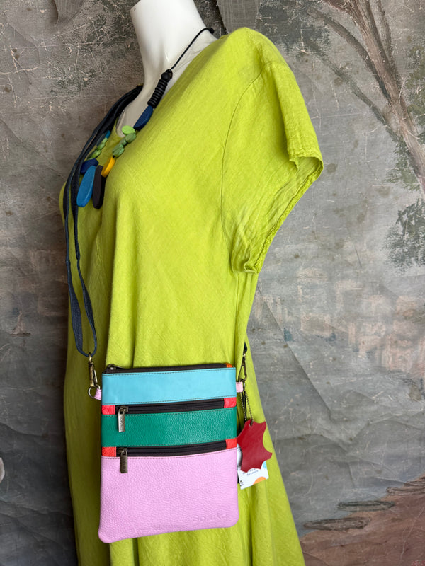 Colorblock crossbody bag in teal, green, and pink with zip pockets on lime green dress mannequin - 15