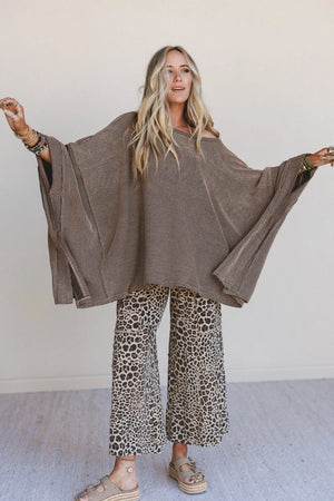 Woman wearing oversized brown ribbed knit tunic top with wide sleeves paired with leopard print wide-leg pants - 1